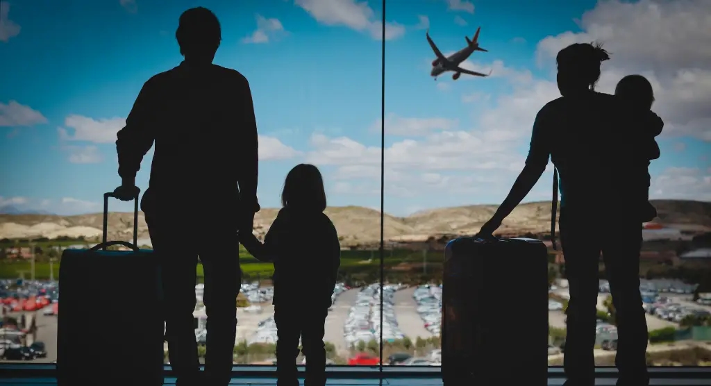 silhouette of a family of four looking out a window and seeing an airplane